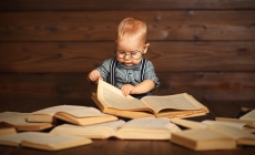 Foto van baby met bril tussen stapel met boeken